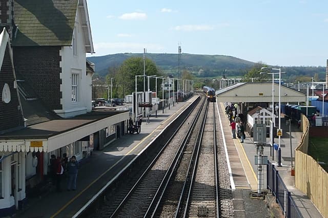 Petersfield railway station platform with train approaching and Butser Hill visible in the background